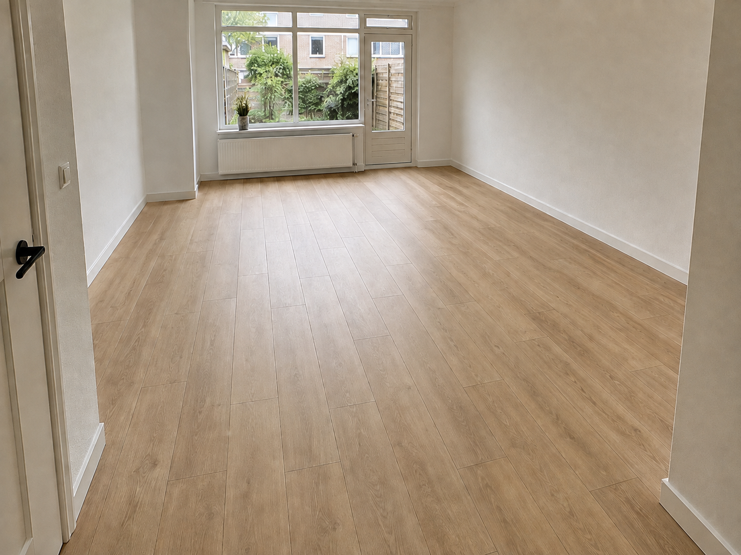 Projecten Net gelegde naturel eiken laminaatvloer in een lege Nederlandse woonkamer